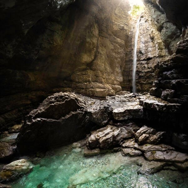 Tirage d'Art "Souterrain de vie" d'une cascade entrant dans un caverne créant un petit lac souterrain aux couleurs vives