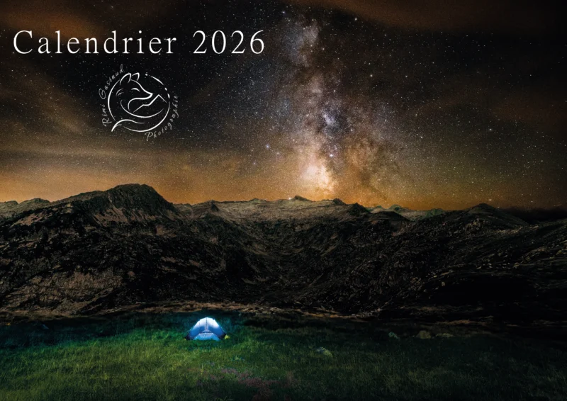 Première de couverture du calendrier 2026 montrant la photo "Unité et Tout". La photo montre une scène nocturne d'une tente bleue éclairée de l'interieur face à une montagne surplombée par la voie lactée.